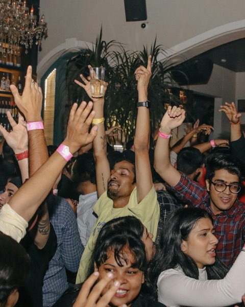 A packed bar with everyone’s hands in the air