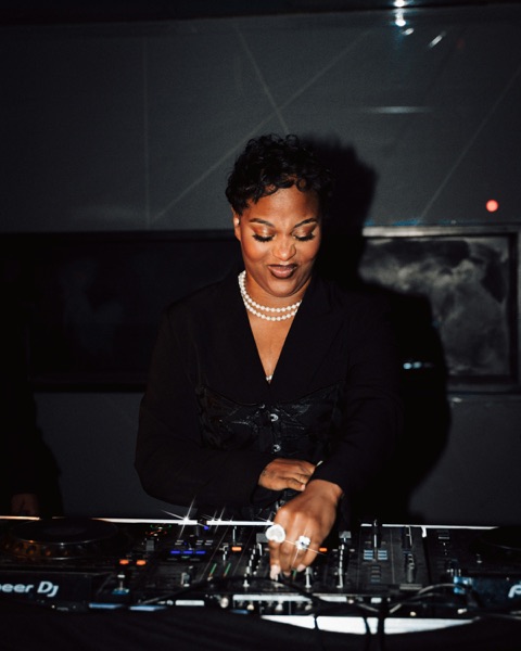 A DJ smiling as she mixes at the decks