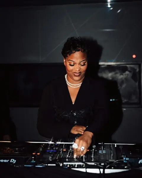 A DJ smiling as she mixes at the decks