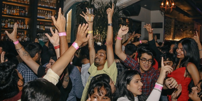 A packed bar with guests' hands in the air