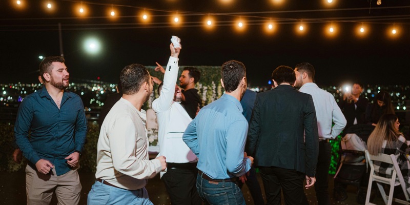 Guests dancing under string lights at an outdoor private party