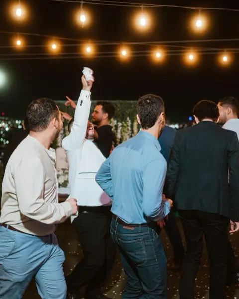 Guests dancing under string lights at an outdoor party